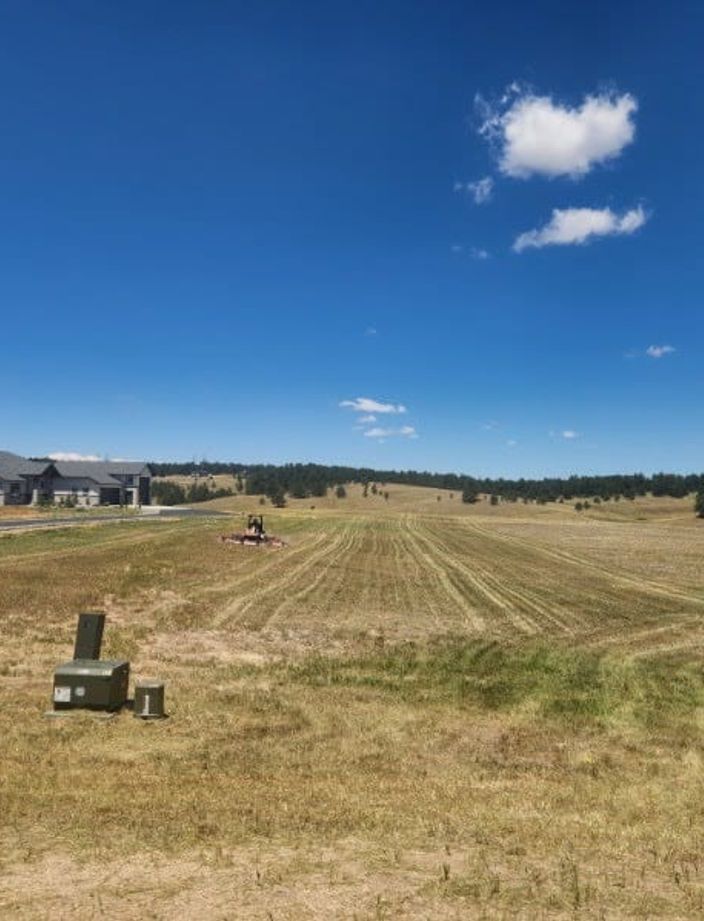 Freshly mowed field with visible cut rows behind a custom home outside Colorado Springs