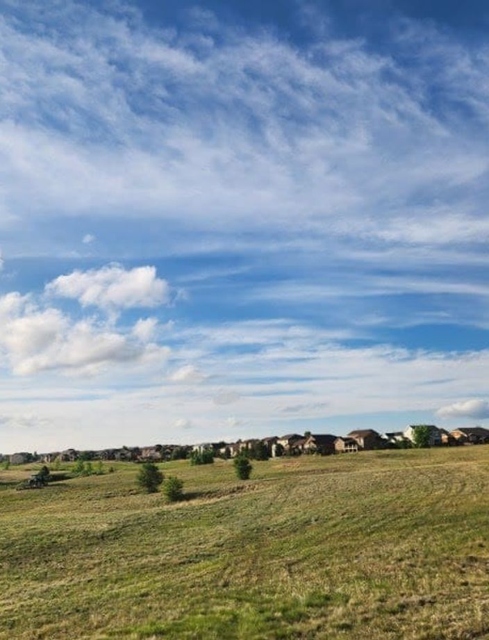 Green field mowed to an even height under a wide Colorado sky
